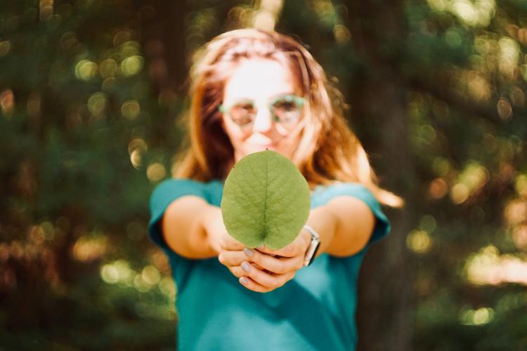 mert guller jFBWOaoS 7o unsplash Mujer con hoja en la mano.