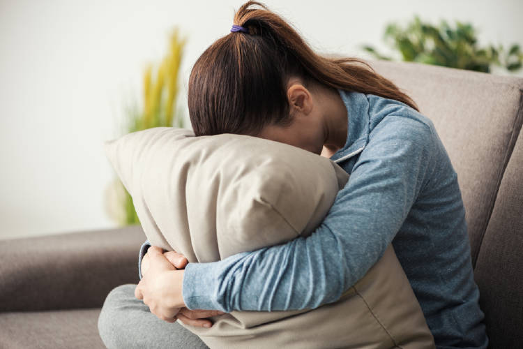 mujer apoya su cabeza contra una almohada en señal de agotamiento