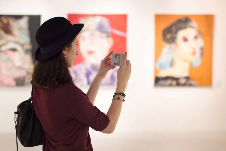 museo joven observa obras de arte y las captura con su movil en un museo de arte moderno