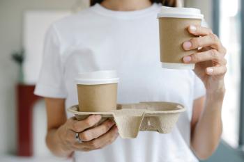 Persona sosteniendo vasos descartables de café