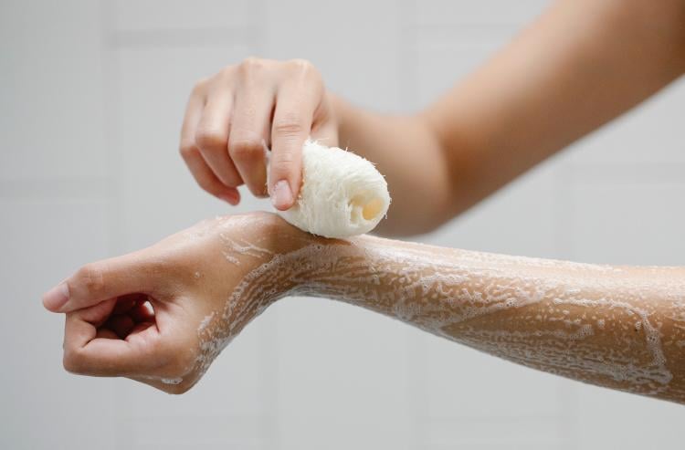 Persona exfoliando su piel con una esponja vegetal