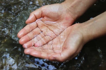 dos manos sostienen el agua de un rio 