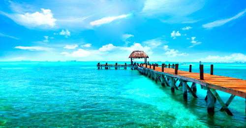 Cielo azul con pocas nubes, muelle de madera con con una choza al final, sobre un mar de aguas cristalinas y color turquesa 