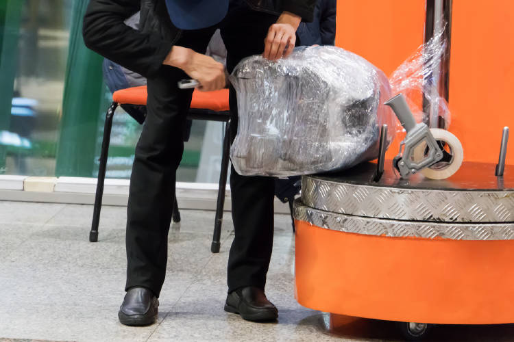 valija envuelta en plastico trabajador del aeropuerto envuelve en plastico una maleta