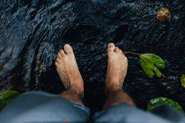 Un hombre moja sus pies en el agua