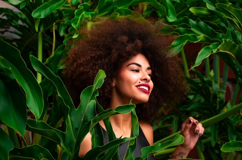 Una mujer con un afro entre hojas de plantas