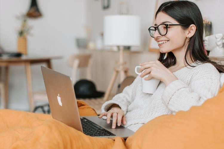 Mujer realiza trabajo remoto con su ordenador tomando café