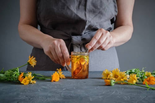 mujer prepara medicina herbal con flores