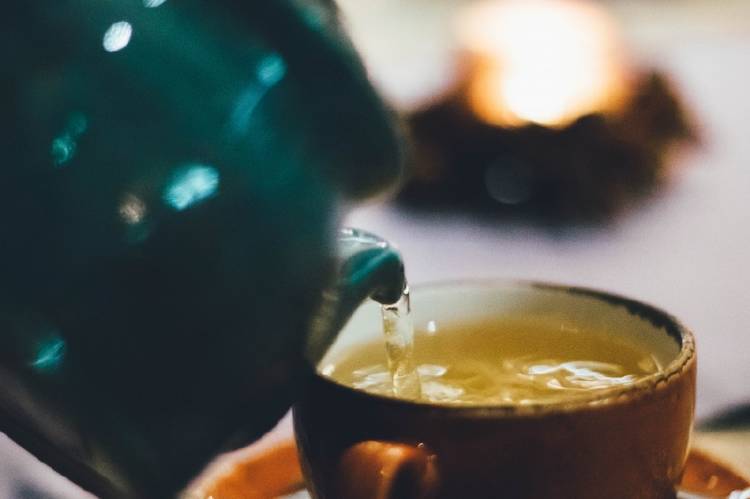 Sirviendo agua en una taza de té con una tetera