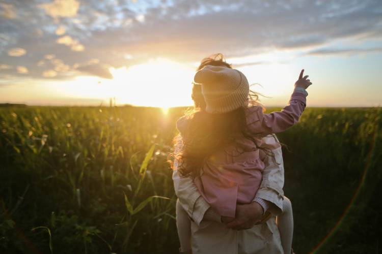 Una mujer con su hija en un campo al atardecer