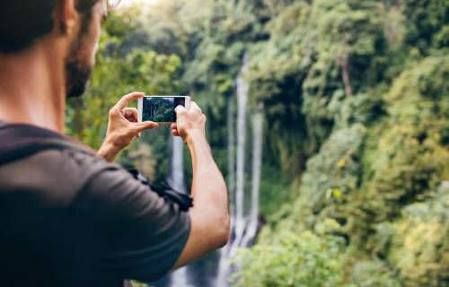 Un hombre toma una foto de una cascada