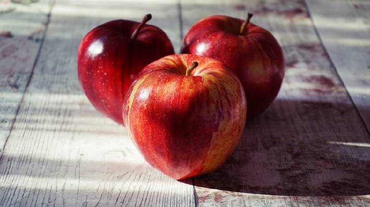 Tres manzanas rojas sobre una mesa