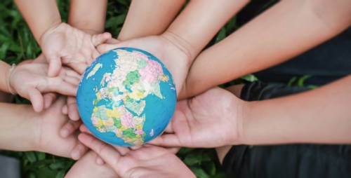 manos de pequeños sostienen la representacion del planeta tierra buscando construir un mundo mejor