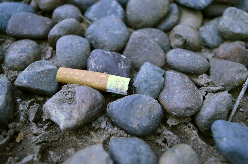 Una colilla de cigarrillo tirada en un suelo de piedras