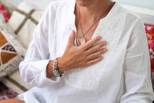 chakra corazon mujer lleva su mano hacia su pecho, el centro de energia emocional