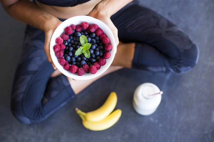 Una mujer sostiene un recipiente con frutas