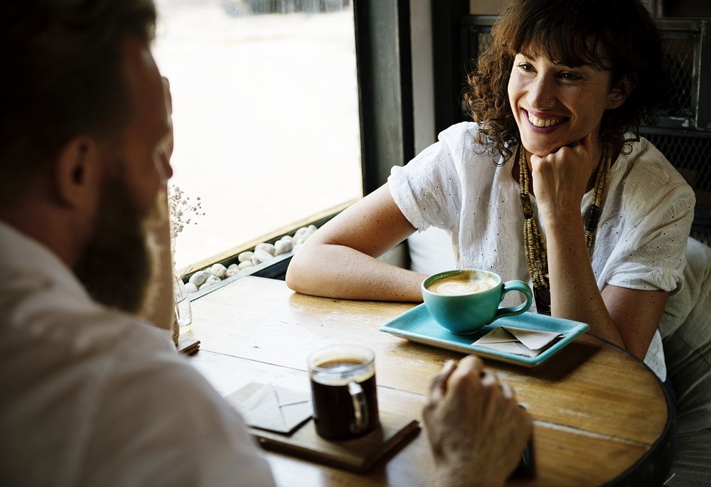 Un hombre y una mujer conversan y toman café en un bar