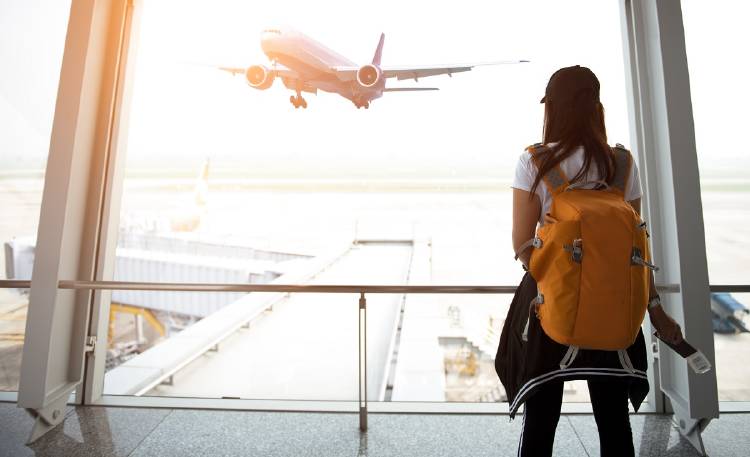 Una joven mira un avión que despega en un aeropuerto