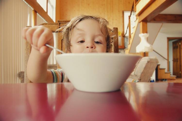 Un niño comiendo de un recipiente