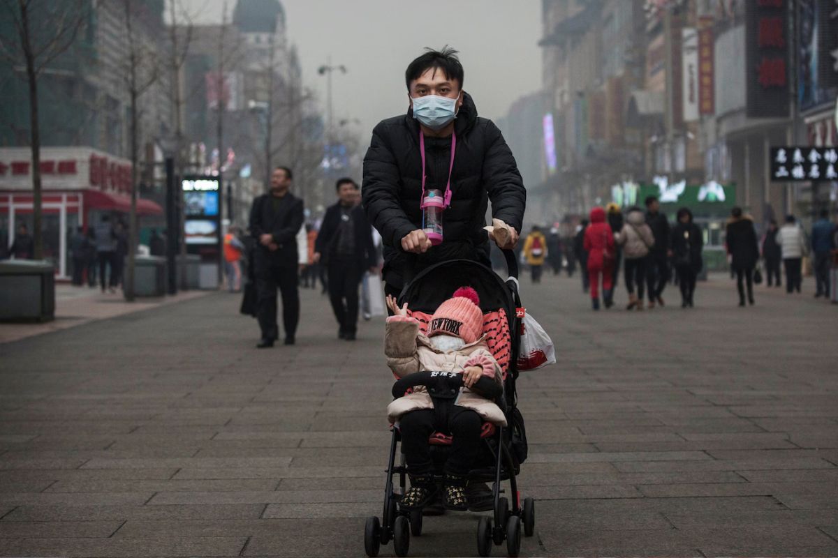A Chinese man and his child wear masks to protest against pollution as they walk through a shopping area in Beijing. (Kevin Frayer/Getty Images)