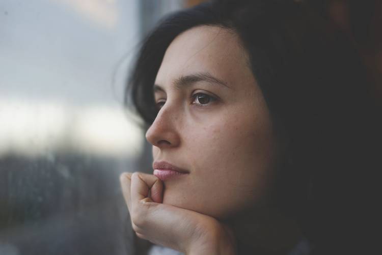 Una mujer mira por la ventana pensativa