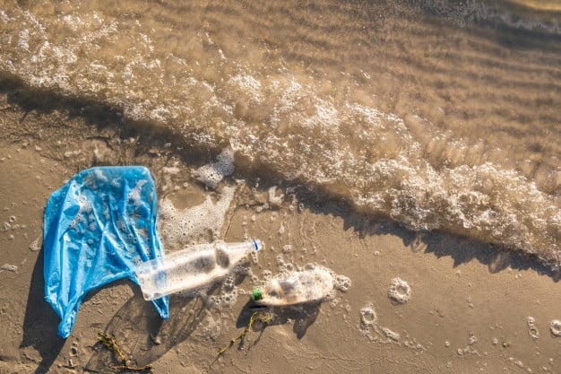 bolsa plastico botellas playa orilla mar concepto contaminacion agua basura paquete comida vacia tirada orilla mar vista superior olas agua arena_145134 433