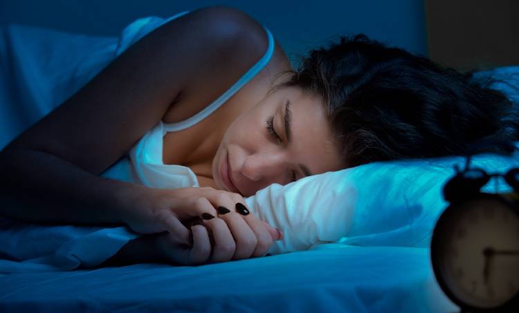 Unamujer durmiendo con un reloj a su lado