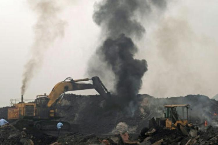 INDIA Una columna de humo se eleva mientras un trabajador maneja una excavadora para transportar montones de carbón en bruto en las afueras de Dhanbad, en el estado indio de Jharkhand© Vishal kumar singh