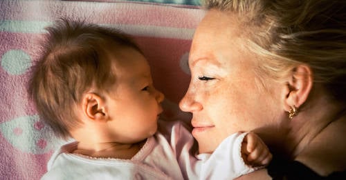 hija recien nacida y madre acostadas en la cama mirandose