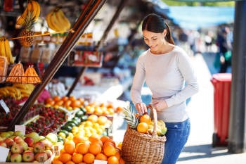 mujer compra frutas y verduras climatéricas en un mercado local