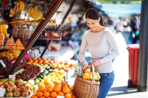 mujer compra frutas y verduras climatéricas en un mercado local