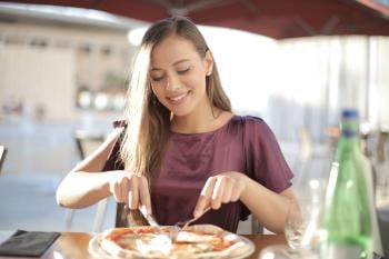 Mujer comiendo pizza en un restaurante