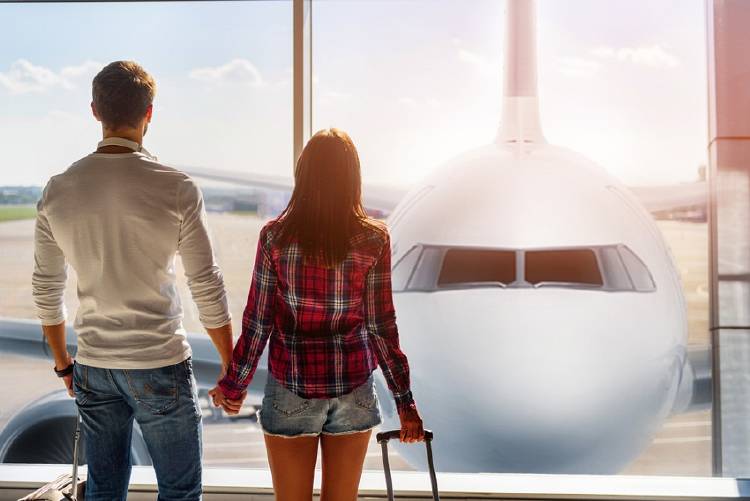 pareja tomada de la mano frente a avion en aeropuerto