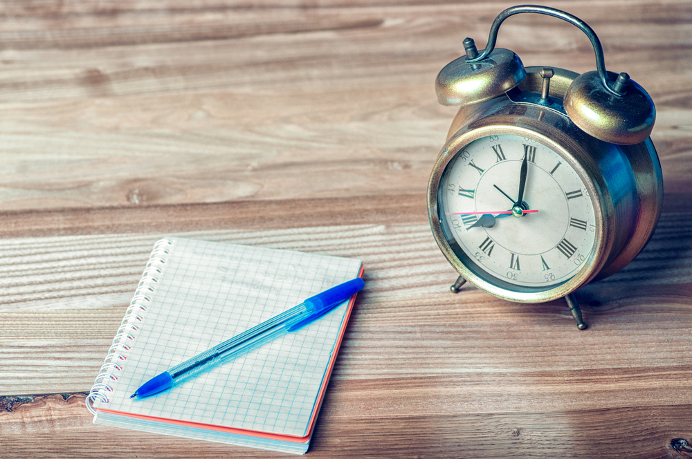 diario de sueño Un cuaderno al lado de un reloj despertador