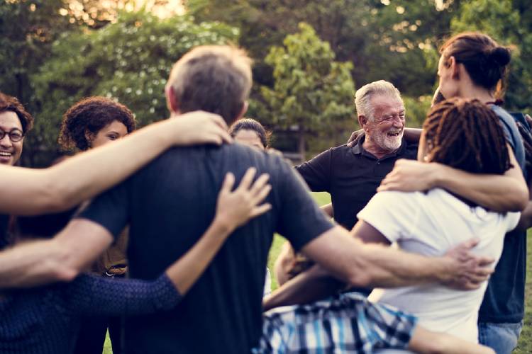 personas de todas las edades se abrazan al aire libre