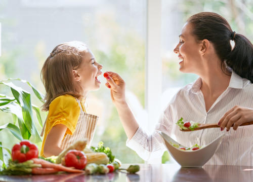 shutterstock_1160689900 Niña come con su madre