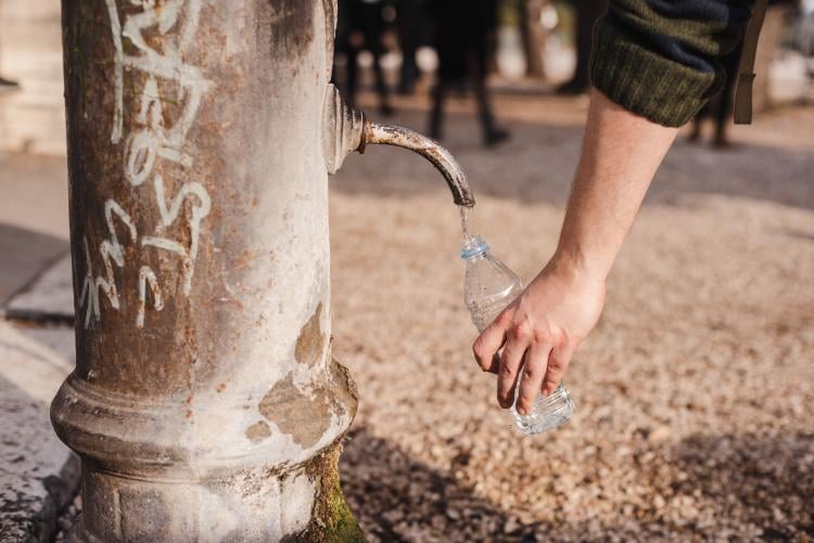 Persona llenando una botella de agua en el parque