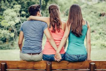 infidelidad Un hombre abraza a su pareja y toma la mano de otra mujer por detrás