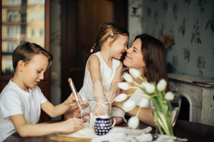 Madre con una niña en brazos y un niño