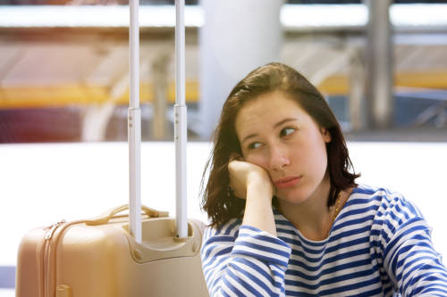 mujer con su valija espera cansada en el aeropuerto