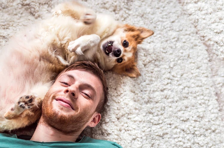 Un hombre recostado en el suelo con su perro