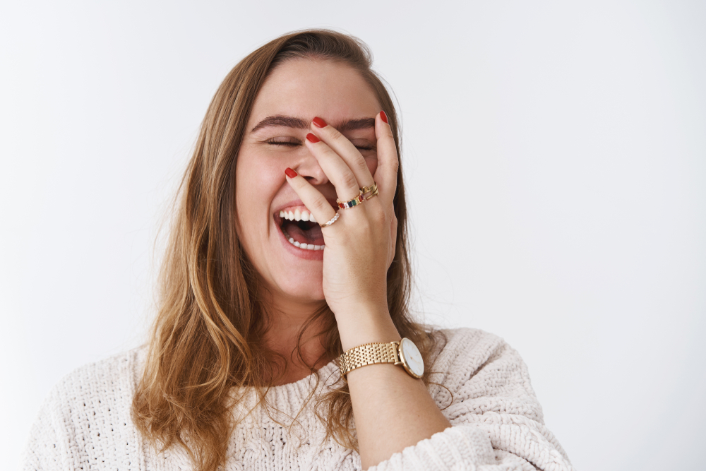 risas mujer de pelo rubio vestida de rosa se ríe a carcajadas