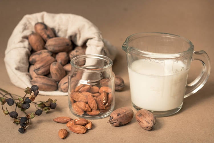 Leche en una jarra medidora con almendras alrededor