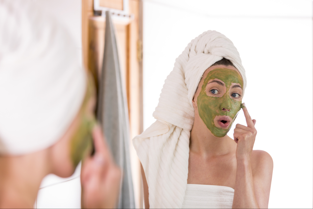 Una mujer se aplica una mascarilla verde en el rostro