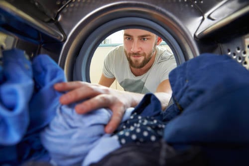 Un hombre mete ropa en la lavadora