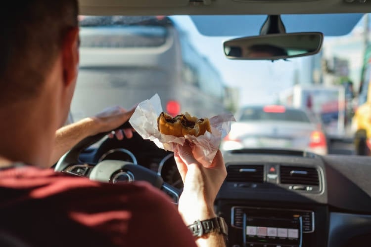 hombre come hamburguesa en el auto