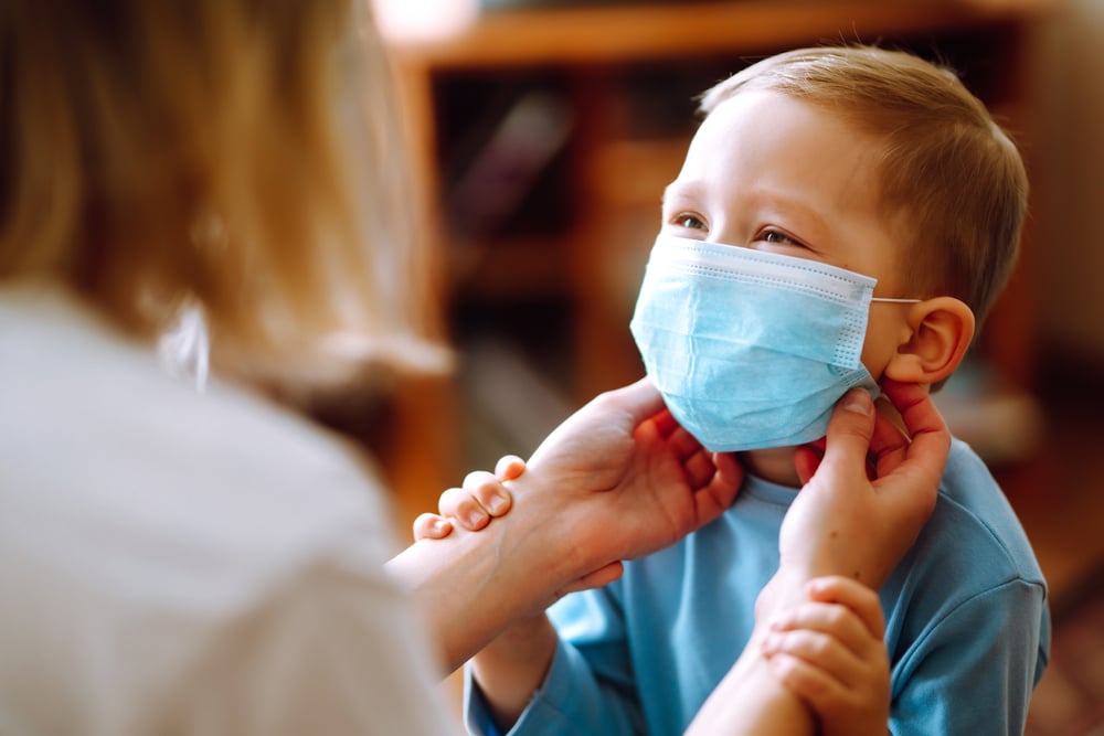 Mujer acomoda la mascarilla de un niño