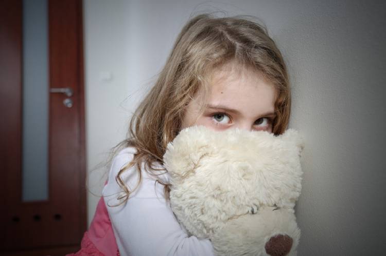 niña triste Una niña con mirada triste abraza su oso de peluche