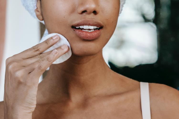 Mujer limpiando su rostro con algodón