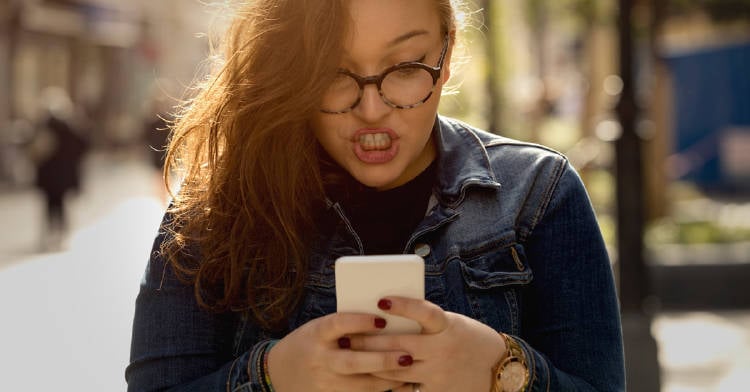 mujer caminando por la calle enojada por algo que vio en su celular